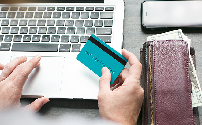 A Person Working on a Laptop while Holding a Card