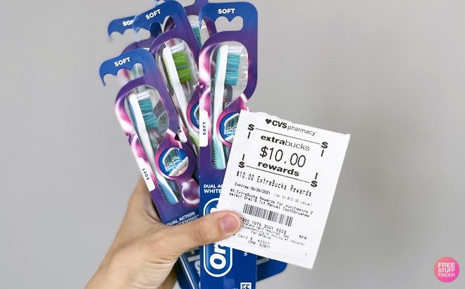A Hand Holding Toothbrushes and CVS ExtraBucks A Hand Holding Toothbrushes and CVS ExtraBucks